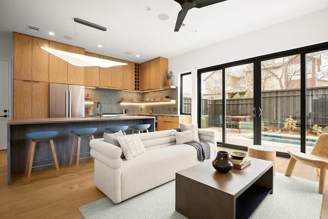 living area with light wood-style flooring, visible vents, a ceiling fan, and recessed lighting