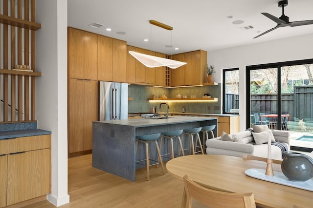 kitchen featuring high end fridge, visible vents, light wood-style flooring, and modern cabinets