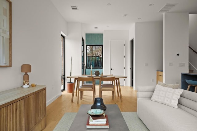 living room featuring stairs, light wood-type flooring, and visible vents