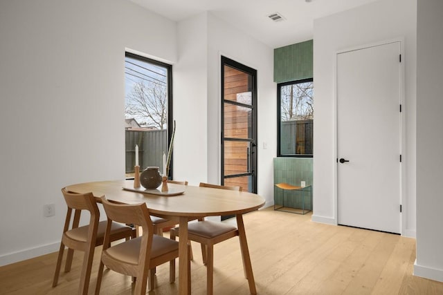 dining space with baseboards, visible vents, and light wood-style floors