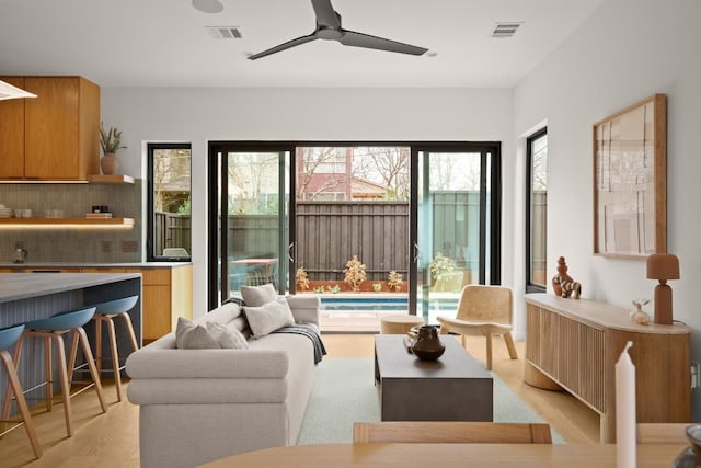 living area with a ceiling fan, visible vents, and light wood-style flooring