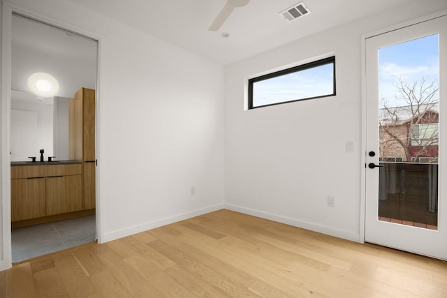 spare room featuring light wood-style flooring, visible vents, ceiling fan, and baseboards