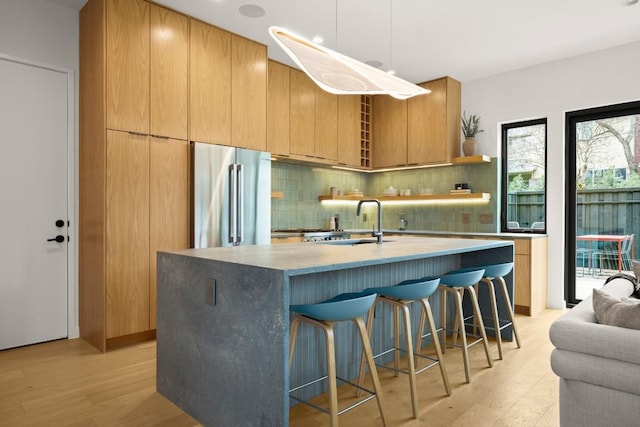 kitchen featuring high end fridge, a sink, decorative backsplash, and modern cabinets