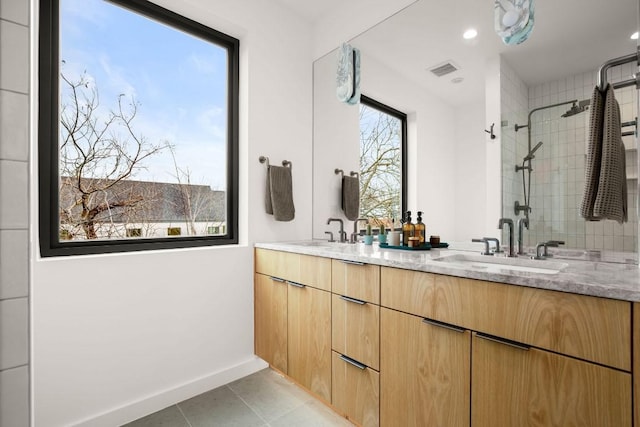 bathroom featuring tile patterned flooring, visible vents, a sink, and tiled shower