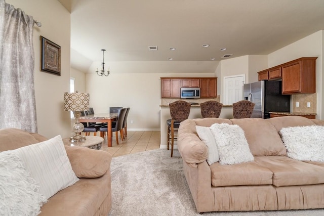 living area featuring light tile patterned floors, a chandelier, visible vents, and baseboards