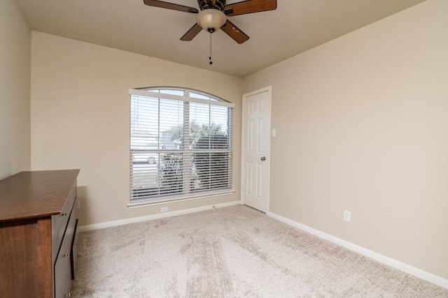 carpeted empty room featuring ceiling fan and baseboards