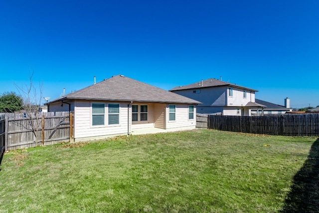 rear view of property featuring a fenced backyard, a shingled roof, and a yard