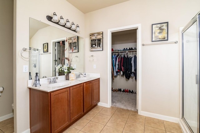 full bath with tile patterned flooring, a sink, a shower stall, double vanity, and a walk in closet