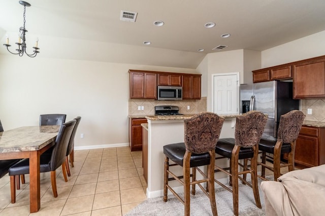 kitchen with stainless steel appliances, visible vents, a notable chandelier, and light tile patterned floors