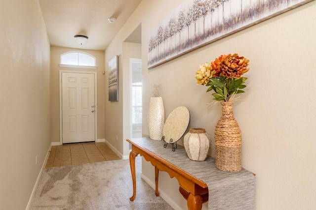 doorway to outside with carpet, baseboards, and tile patterned flooring