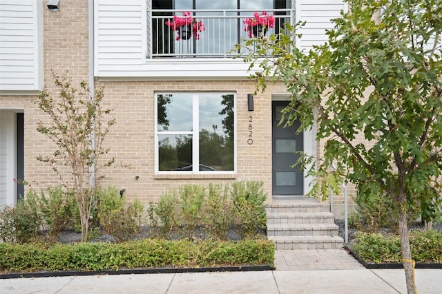 doorway to property with brick siding and a balcony