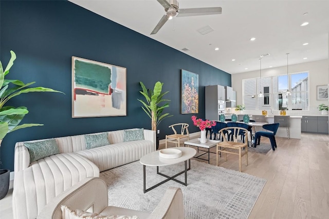 living area with light wood-style floors, an accent wall, recessed lighting, and a ceiling fan