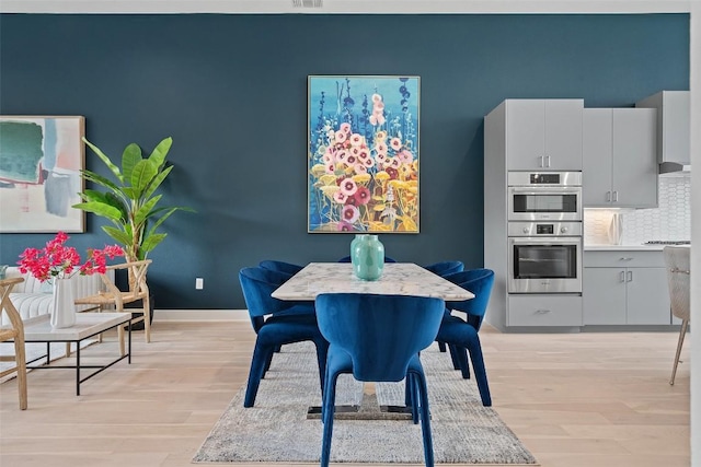 dining room featuring light wood finished floors, visible vents, and baseboards