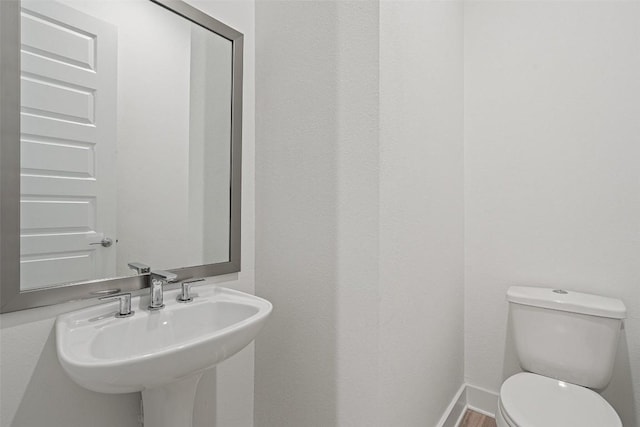 bathroom with a sink, toilet, and baseboards