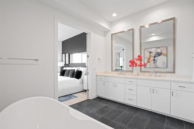 ensuite bathroom with double vanity, a freestanding tub, a sink, and ensuite bathroom