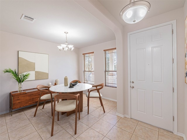 dining area with arched walkways, a notable chandelier, light tile patterned floors, visible vents, and baseboards