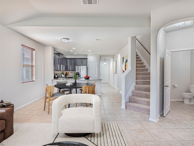 dining area featuring arched walkways, light tile patterned floors, visible vents, baseboards, and stairs