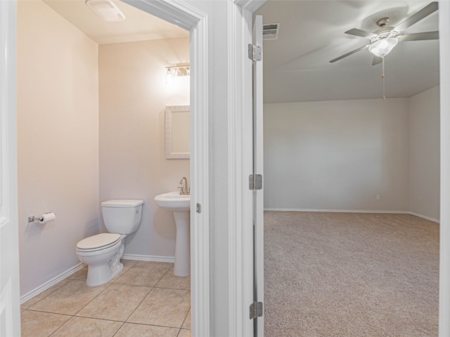 half bathroom with ceiling fan, toilet, a sink, visible vents, and tile patterned floors