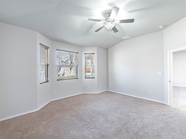 carpeted empty room with ceiling fan, visible vents, vaulted ceiling, and baseboards