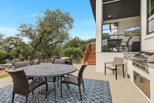 view of patio with outdoor dining space, stairway, area for grilling, and exterior kitchen