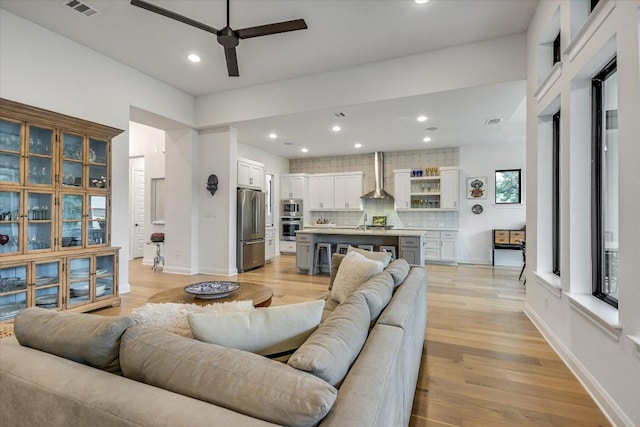 living room featuring light wood-type flooring, visible vents, baseboards, and recessed lighting