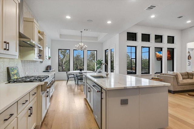 kitchen with a raised ceiling, light wood-style flooring, a sink, and visible vents