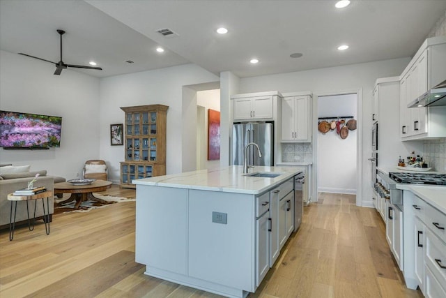 kitchen with stainless steel appliances, visible vents, light wood-style floors, open floor plan, and a sink