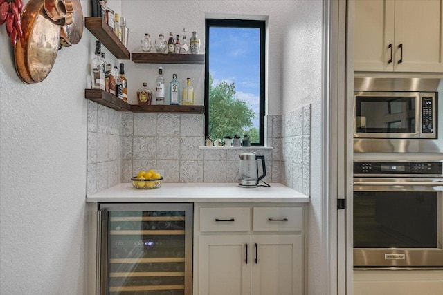 bar featuring stainless steel appliances, wine cooler, a bar, and tasteful backsplash