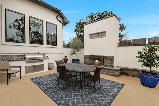 view of patio / terrace featuring an outdoor stone fireplace, outdoor dining area, exterior kitchen, and area for grilling