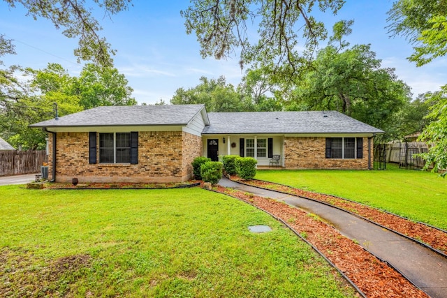 single story home with brick siding, roof with shingles, a front yard, and fence