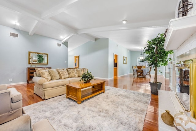 living area featuring vaulted ceiling with beams, baseboards, visible vents, and wood finished floors