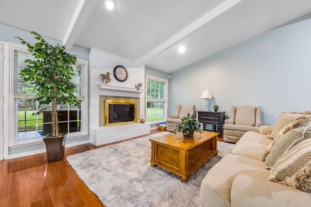 living area featuring lofted ceiling with beams, a brick fireplace, baseboards, and wood finished floors