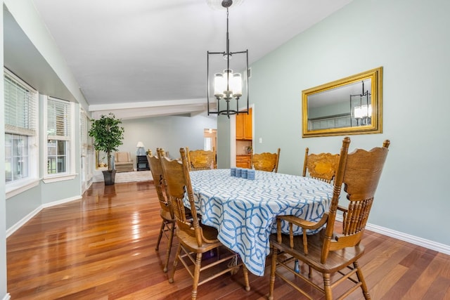 dining room with lofted ceiling, an inviting chandelier, baseboards, and wood finished floors