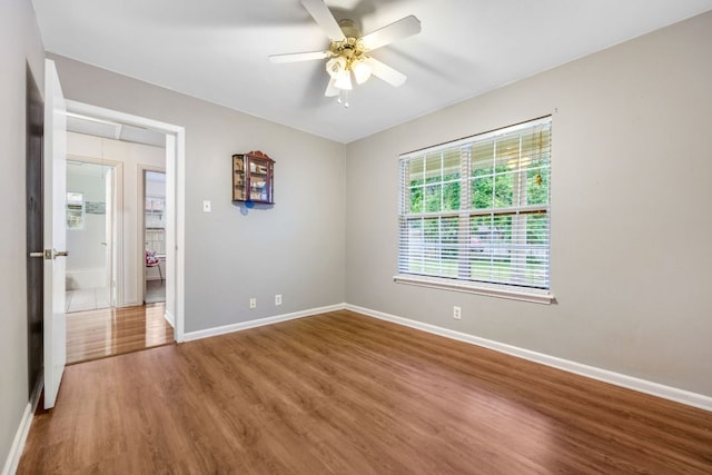 spare room featuring ceiling fan, attic access, baseboards, and wood finished floors