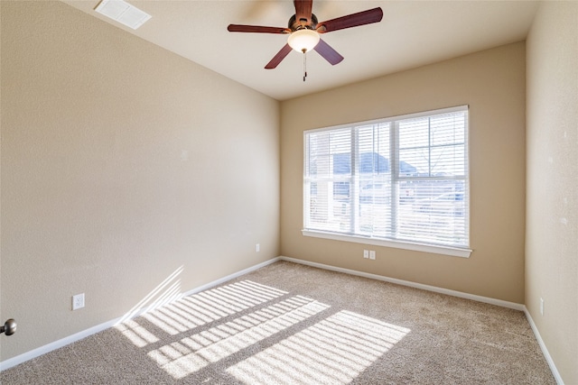 empty room with a ceiling fan, light colored carpet, visible vents, and baseboards