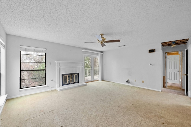 unfurnished living room with carpet, plenty of natural light, baseboards, and a glass covered fireplace