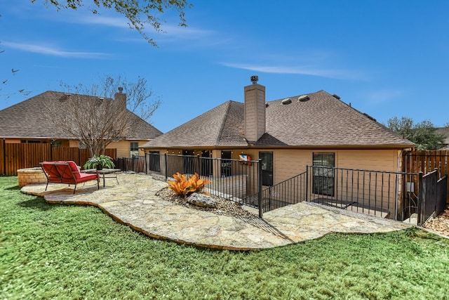 rear view of property with a fenced backyard, roof with shingles, a lawn, and a patio