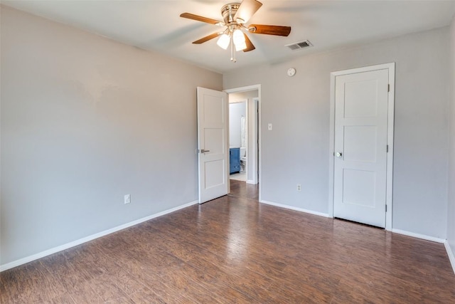 spare room featuring dark wood-style floors, a ceiling fan, visible vents, and baseboards