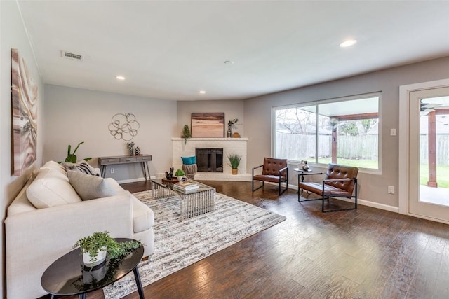 living area with dark wood-style floors, a brick fireplace, visible vents, and recessed lighting