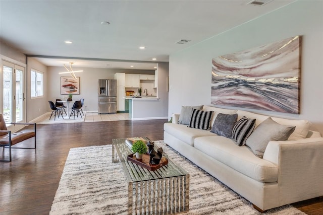 living area featuring light wood-style floors, recessed lighting, visible vents, and baseboards