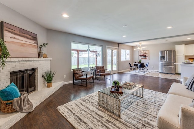 living area featuring light wood-type flooring, a fireplace, baseboards, and recessed lighting