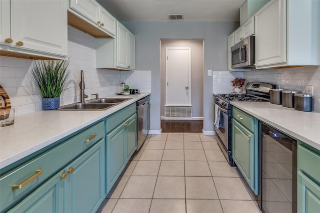 kitchen with stainless steel appliances, light countertops, white cabinetry, and a sink