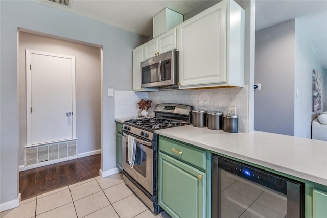 kitchen featuring visible vents, white cabinets, decorative backsplash, wine cooler, and appliances with stainless steel finishes