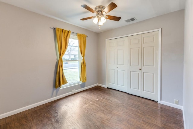 unfurnished bedroom featuring wood finished floors, a ceiling fan, visible vents, baseboards, and a closet