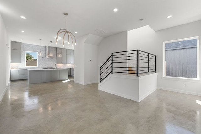 unfurnished living room with stairs, finished concrete floors, and baseboards