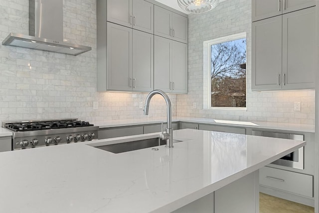 kitchen featuring range, a sink, gray cabinets, wall chimney range hood, and backsplash