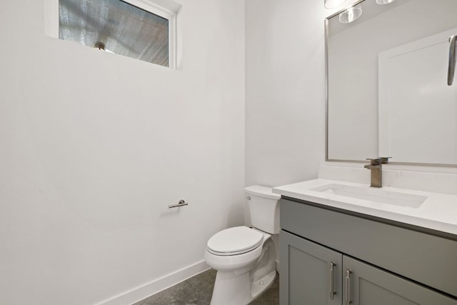 half bath with toilet, baseboards, and vanity