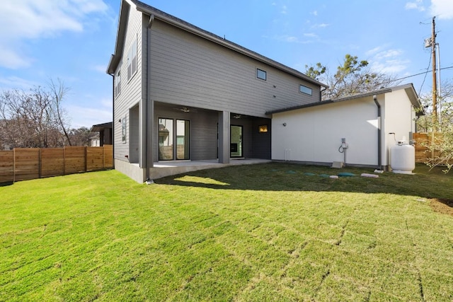 rear view of property featuring a patio area, fence, and a lawn