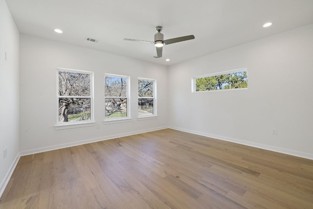 spare room with wood finished floors, visible vents, and baseboards