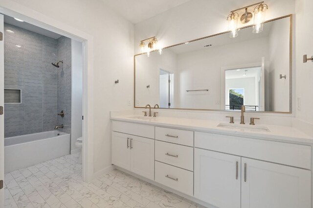 full bathroom with marble finish floor, double vanity, a sink, and toilet
